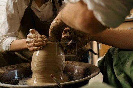 Foto de Taller de cerámica alfarero trabaja con el producto de la rueda del alfarero hecho de alfarero de arcilla conduce clase magistral - Imagen libre de derechos