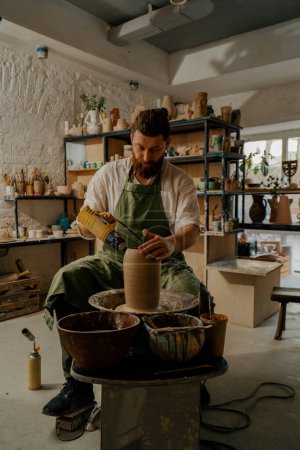 Téléchargez les photos : Un potier tire un vase sur la roue du potier dans un atelier de poterie - en image libre de droit