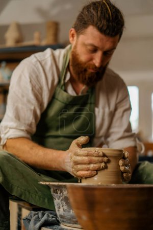 Photo for Pottery workshop A potter works with clay on potter's wheel pottery tools - Royalty Free Image