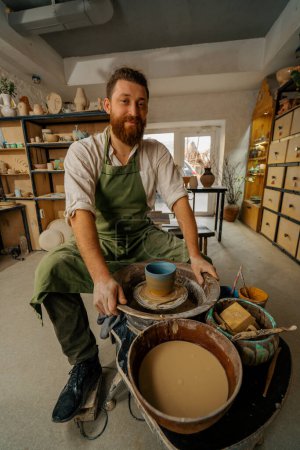 Téléchargez les photos : Atelier de poterie Potier satisfait avec son produit fini sur la roue du potier - en image libre de droit