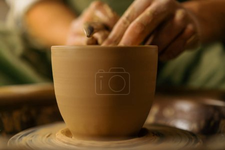 Photo for Pottery workshop potter paints jug with brush and paint on potter's wheel - Royalty Free Image
