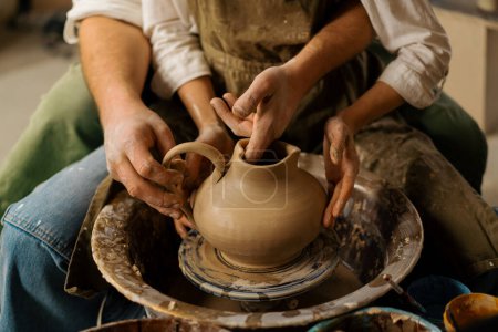 Photo for Pottery workshop a potter teaches a student to sculpt a jug from clay sculpting handle for jug - Royalty Free Image