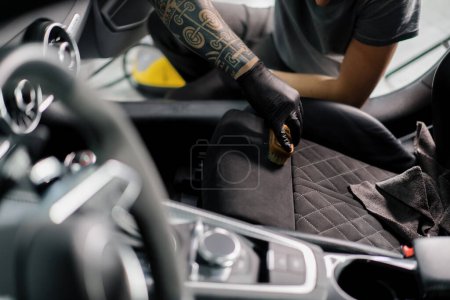 Téléchargez les photos : Nettoyage de l'intérieur de la voiture avec une brosse Une voiture détaillant travailleur nettoyage intérieur de la voiture et siège avec brosse et mousse le concept de détails de voiture - en image libre de droit