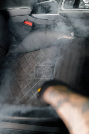 Foto de El concepto de la limpieza y el detalle del coche El maestro de detalles limpia el interior del coche con un limpiador de vapor caliente Limpieza interior del coche - Imagen libre de derechos