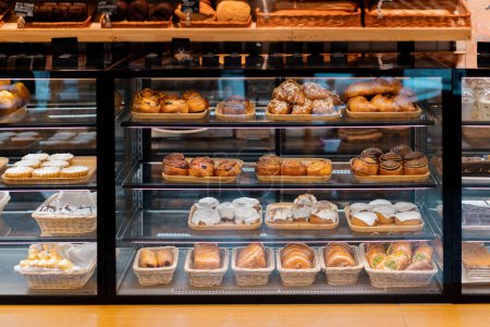 Foto de Contador lleno de deliciosos bollos y pasteles en la tienda, panadería - Imagen libre de derechos
