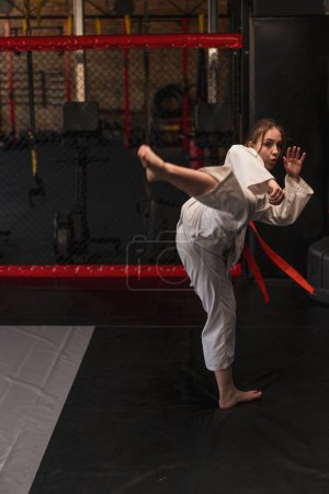 Téléchargez les photos : Fille pratique le karaté en gymnase femme en kimono pratique des mouvements et pose des arts martiaux - en image libre de droit