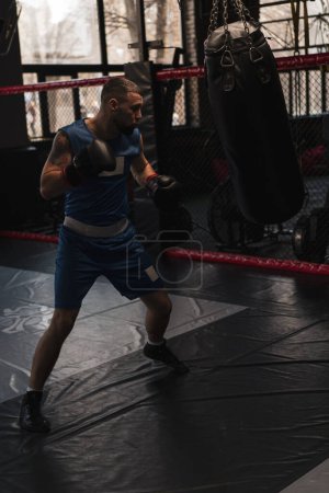 Photo for Boxing gym a boxer trains his punches hitting punching bag - Royalty Free Image