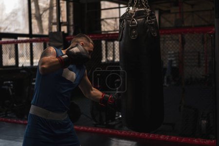 Téléchargez les photos : Boxe gymnase un boxeur entraîne ses coups frapper sac de boxe - en image libre de droit