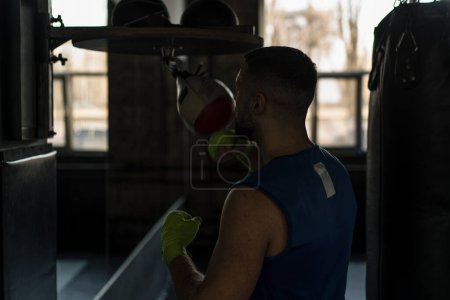 Photo for A boxer practicing a speed exercise with a small punching bag in boxing gym - Royalty Free Image