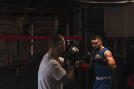 Photo for Boxer Practices His Punches with His Coach in Boxing Gym - Royalty Free Image