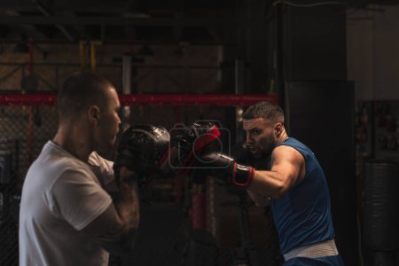 Foto de Boxeador practica sus golpes con su entrenador en el gimnasio de boxeo - Imagen libre de derechos