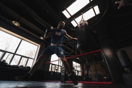 Foto de Boxeo gimnasio un boxeador entrena sus golpes golpeando saco de boxeo - Imagen libre de derechos