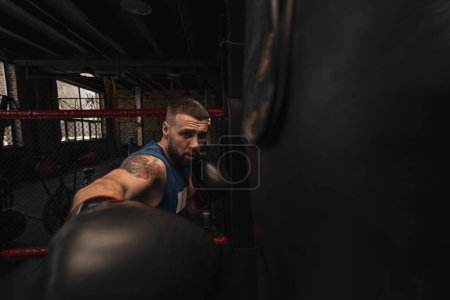 Téléchargez les photos : Boxe gymnase un boxeur entraîne ses coups frapper sac de boxe - en image libre de droit