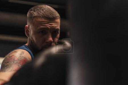 Photo for Boxing gym a boxer trains his punches hitting punching bag - Royalty Free Image