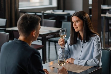 Foto de Una cita en un restaurante de hotel un hombre y una mujer beben vino blanco en vasos cara de una chica sonriente - Imagen libre de derechos