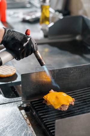 Photo for Professional kitchen in hotel restaurant close-up burger patty with cheese being grilled - Royalty Free Image