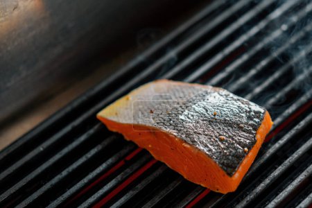 Photo for Professional kitchen in a hotel restaurant close-up of piece of fresh salmon being grilled - Royalty Free Image