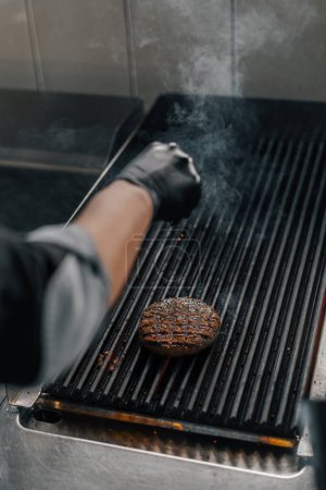 Foto de Cocina profesional en el restaurante del hotel chef está asando una hamburguesa a la parrilla - Imagen libre de derechos