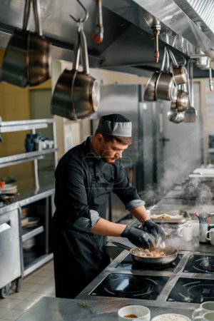 Téléchargez les photos : Cuisine professionnelle dans le restaurant de l'hôtel le chef fait frire des fruits de mer sur la poêle - en image libre de droit