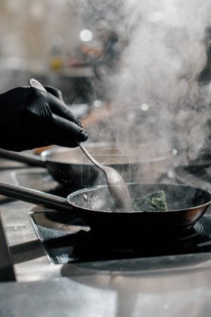 Téléchargez les photos : Cuisine professionnelle dans le restaurant de l'hôtel gros plan du chef préparant des épinards sur la casserole - en image libre de droit