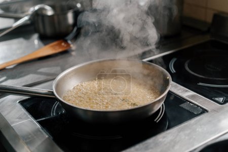 Cocina profesional en el restaurante del hotel primer plano del chef preparando risotto en la estufa