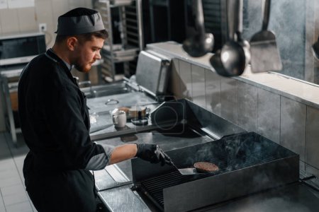 Téléchargez les photos : Cuisine professionnelle dans le chef restaurant de l'hôtel est griller une galette sur un hamburger - en image libre de droit
