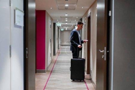 Téléchargez les photos : Un homme avec une valise ouvre la porte d'une chambre d'hôtel un homme d'affaires en voyage concept - en image libre de droit