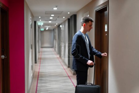 Téléchargez les photos : Un homme avec une valise ouvre la porte d'une chambre d'hôtel un homme d'affaires en voyage concept - en image libre de droit