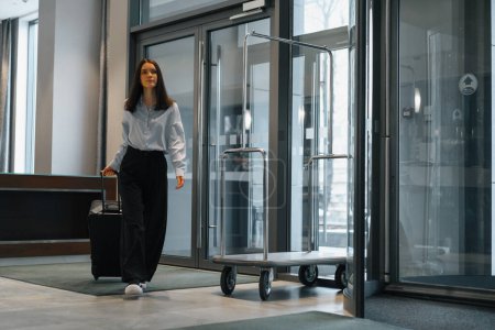 Téléchargez les photos : Une jeune femme d'affaires est arrivée à l'hôtel avec une valise Concept de voyage - en image libre de droit