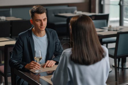 Foto de Una cita en un restaurante del hotel, un hombre y una mujer beben vino blanco en vasos la cara de un hombre serio - Imagen libre de derechos