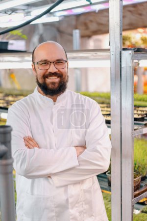 Photo for Portrait of smiling male gardener in glasses and white coat microgreen farm Healthy vegan food Organic plant germination - Royalty Free Image