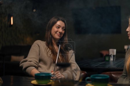Téléchargez les photos : Belle jeune femme inhalant narguilé fille fumeur narguilé assis dans le concept de bar salon détente et fumer - en image libre de droit