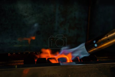 Téléchargez les photos : Charbon pour narguilé rôtis fumeur narguilé avec un brûleur concept de loisirs le processus de fabrication de narguilé - en image libre de droit