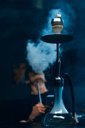 Téléchargez les photos : Narguilé homme à lunettes fumant une pipe traditionnelle narguilé homme expirant fumée dans le café narguilé ou bar-salon - en image libre de droit