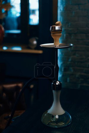 Photo for Hookah bowl with coals a beautiful hookah that smokes stands in a hookah room in muted blue light - Royalty Free Image
