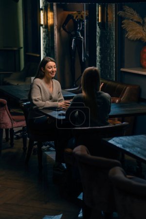 Foto de Dos novias jóvenes se sientan relajados en un bar de narguile y alegremente discutir algo concepto de recreación - Imagen libre de derechos