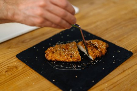 Téléchargez les photos : Chef cuisinier dans la cuisine professionnelle coupe morceaux cuits filet de poulet dans la chapelure - en image libre de droit