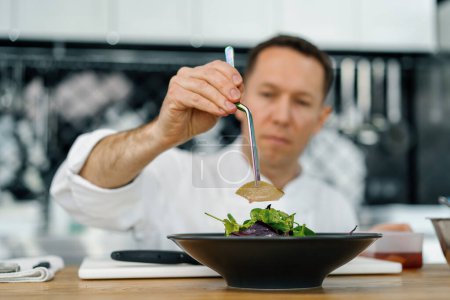 Téléchargez les photos : Chef de cuisine professionnel met des feuilles de salade avec poire et fromage sur l'assiette avec pinces mélange ingrédients d'aliments sains - en image libre de droit