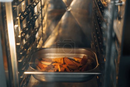 Foto de Las rodajas profesionales de la cocina de patatas con especias en la bandeja para hornear se hornean en el horno - Imagen libre de derechos