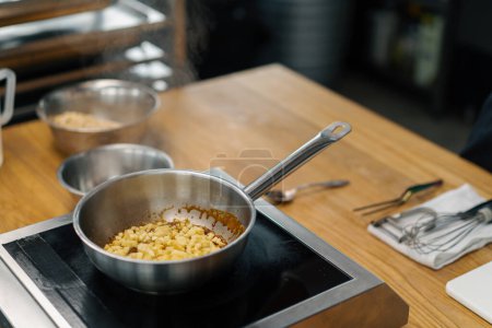 Téléchargez les photos : Chef de cuisine professionnel caraméliser les fruits pour la farine d'avoine dans la casserole préparer le petit déjeuner concept d'alimentation saine - en image libre de droit