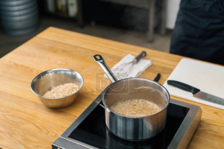 Téléchargez les photos : Petit déjeuner sain Casserole louche en acier inoxydable pleine de porridge avec flocons d'avoine bouillants sur cuisinière Concept de cuisson - en image libre de droit