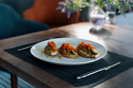 Téléchargez les photos : Pain grillé fraîchement préparé avec de l'avocat rôti et des tomates sur la table au restaurant Concept d'une alimentation saine - en image libre de droit