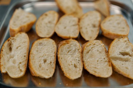 Foto de Cocina profesional rodajas frescas de pan con condimentos se encuentran en la bandeja para hornear primer plano del plato - Imagen libre de derechos
