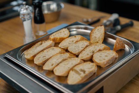 Foto de Cocina profesional rodajas frescas de pan con condimentos se encuentran en la bandeja para hornear primer plano del plato - Imagen libre de derechos