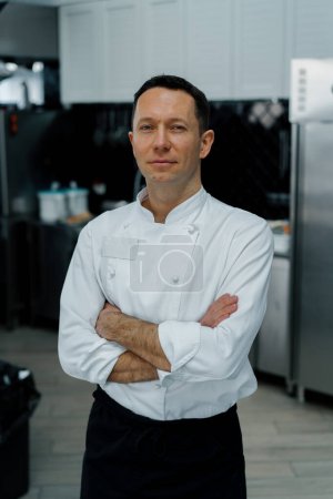 Foto de Profesional cocina sonriente y satisfecho chef blanco abrigo de pie con brazos cruzados retrato - Imagen libre de derechos