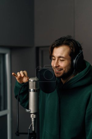 Foto de Cantante de rap con micrófono de auriculares grabando emocionalmente una nueva canción en un estudio de grabación profesional - Imagen libre de derechos