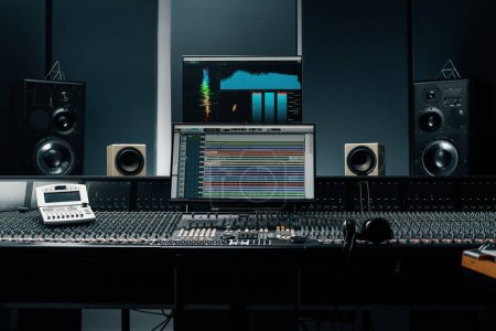 recording studio with a screen with sound wave and volume settings two subwoofers and mixing console