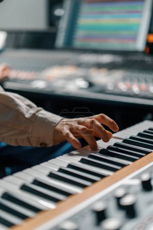 Téléchargez les photos : Clavier piano électronique à main mâle Touches doigt manette midi Musicien produit une chanson en studio d'enregistrement - en image libre de droit