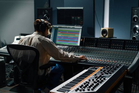 Téléchargez les photos : Ingénieur du son travaillant dans un studio de musique avec moniteurs et égaliseur écran mixage et mastering pistes - en image libre de droit