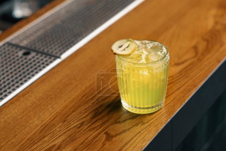 Photo for Close-up of ready-made delicious alcoholic cocktail Apple Smash with kiwi stands on bar and waits for the guest - Royalty Free Image